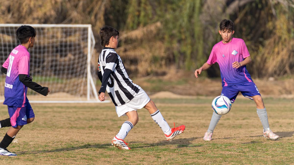 Young people playing a five-a-side football match on grass