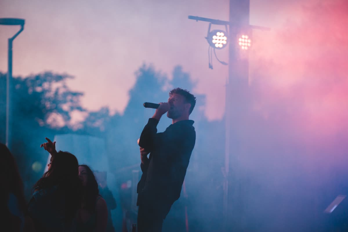 A singer performing live with a guitar on an outdoor stage