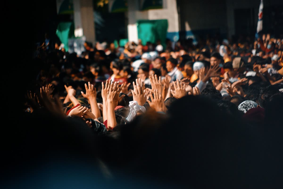 A crowd of young people with hands raised celebrating in front of a stage